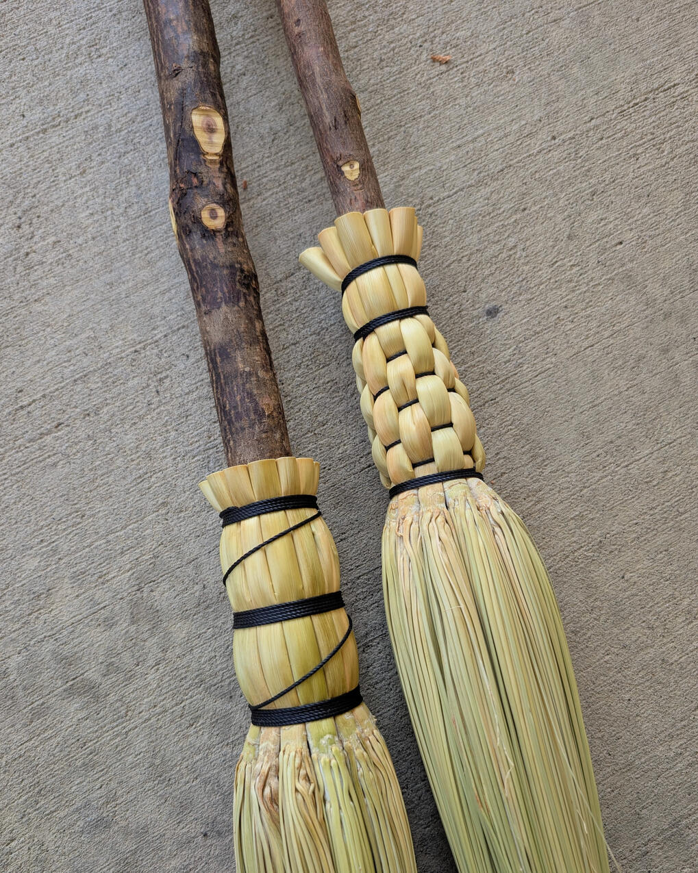 Close up of two cobwebber brooms with rustic handles.