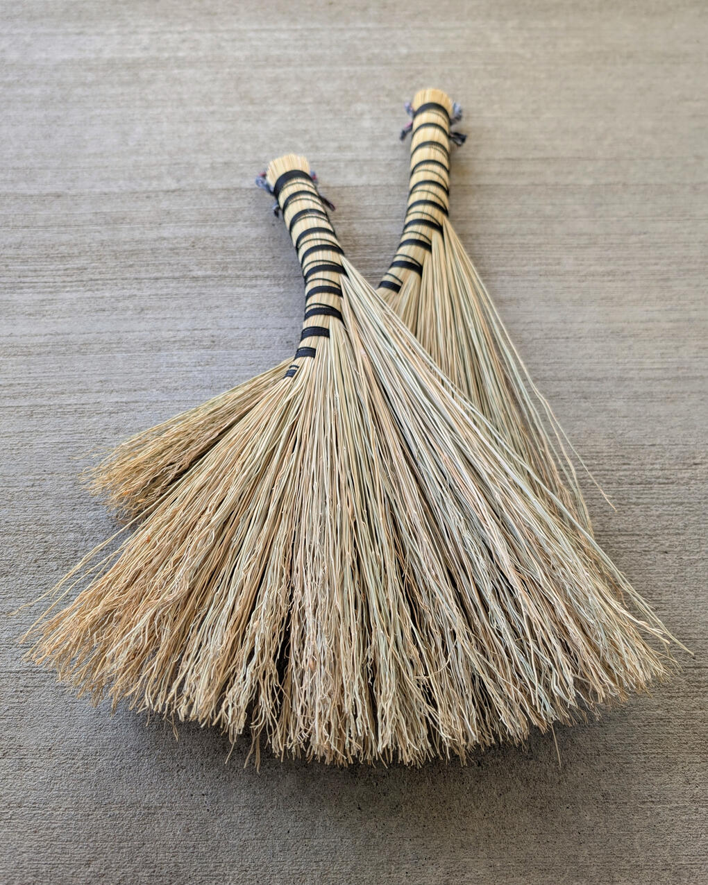 Two handbrooms laying on a concrete background.