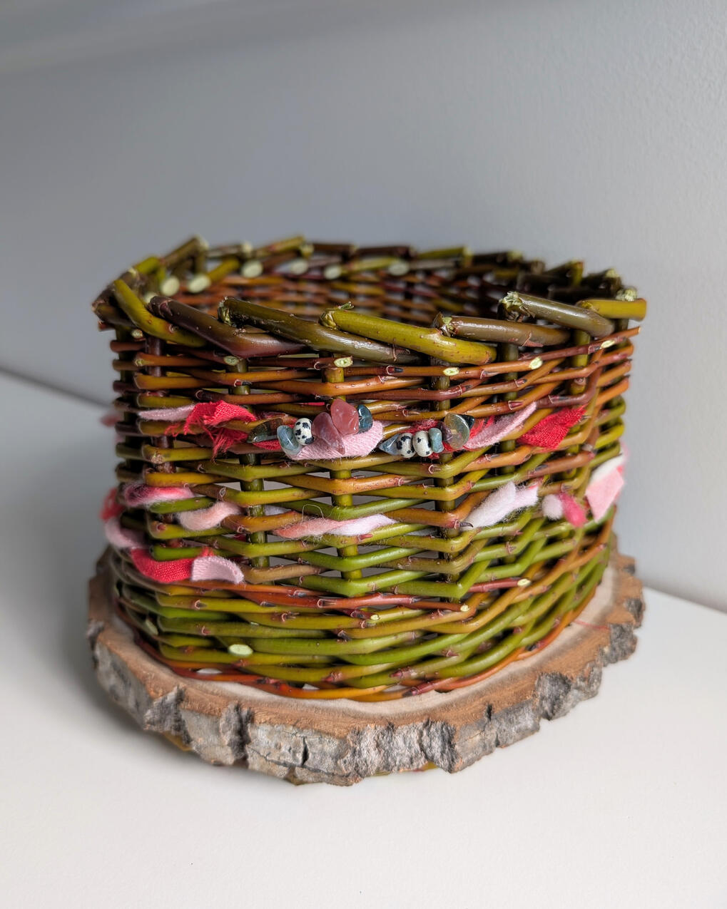 Willow basket with yarn and beads woven into sides.