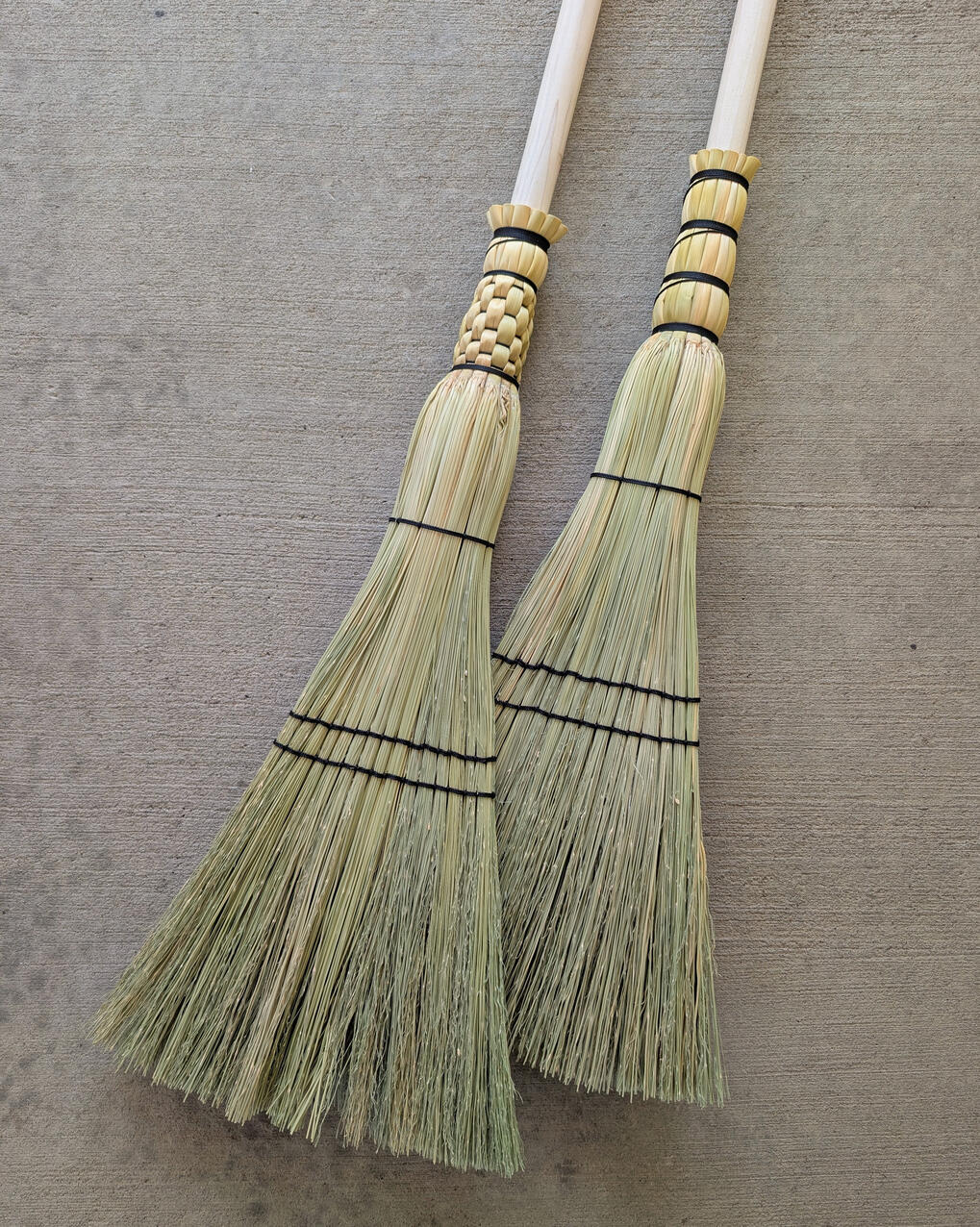 Sweeper Broom Two sweeper brooms laying on concrete background.